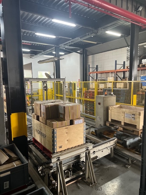 Palet con cajas sobre transportador en la entrada del sistema automático